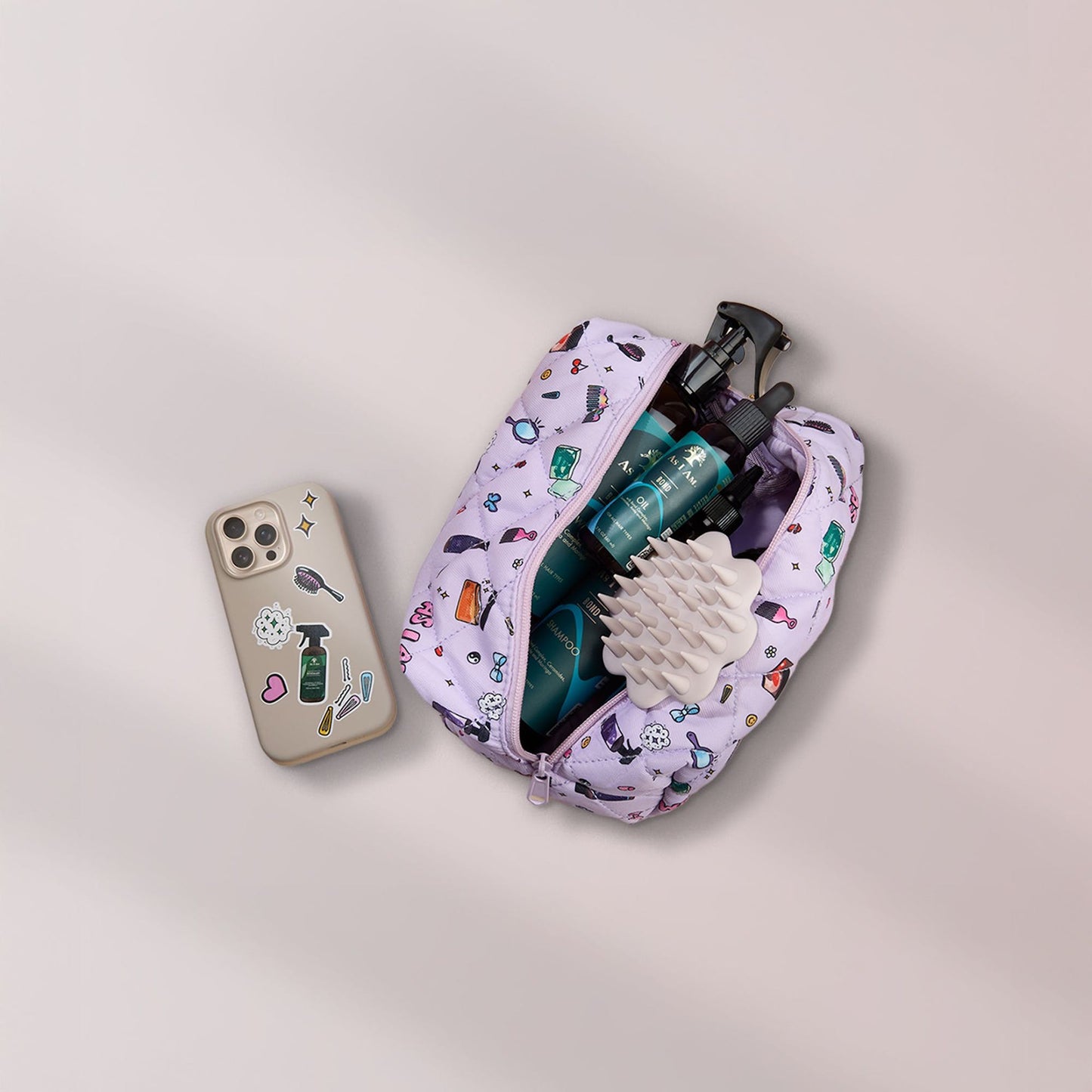 Beige Kopfhautbürste in Kosmetiktasche mit Bond-Produkten und einem Telefon