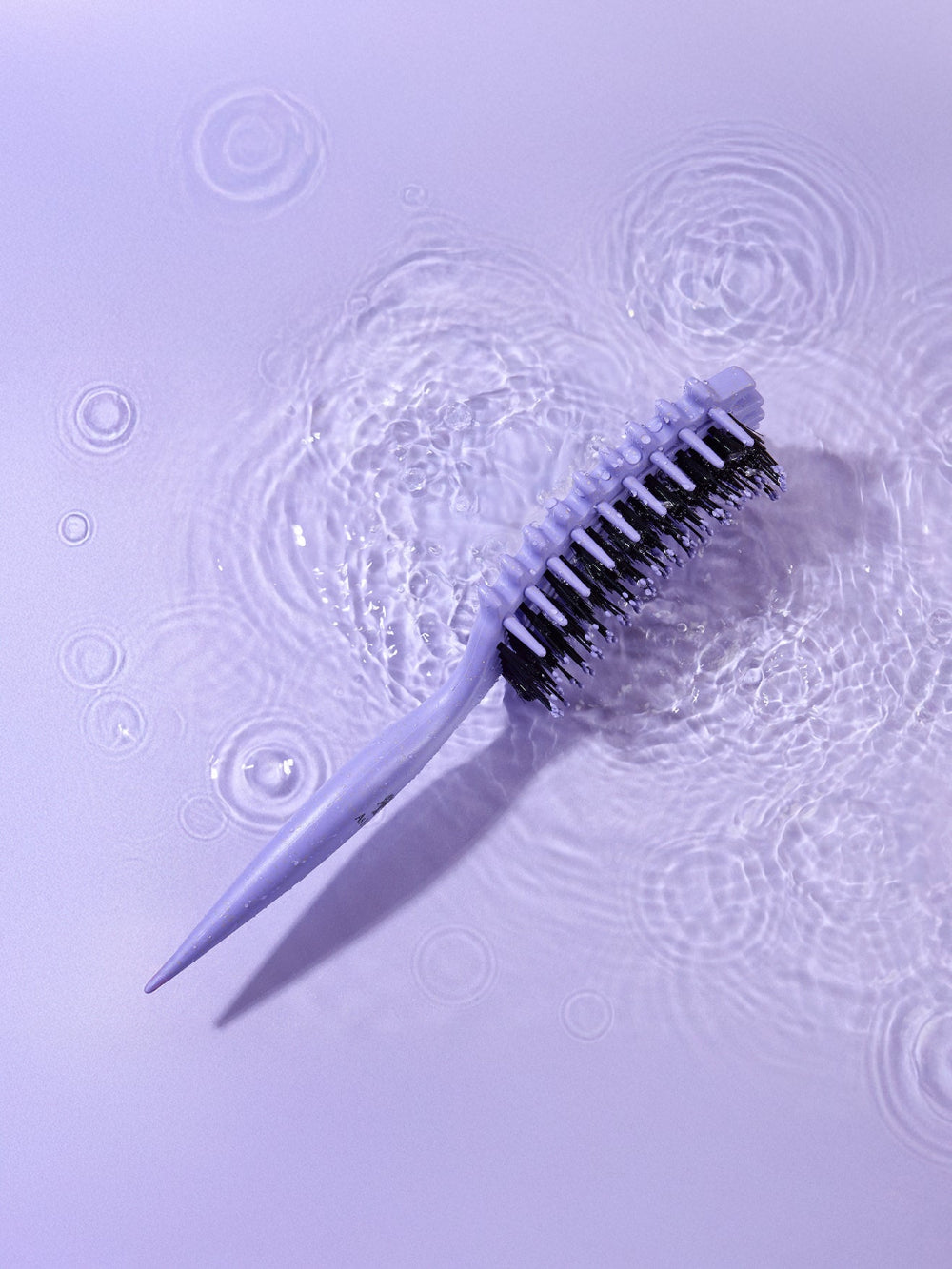 Reinigungsbürste mit Borsten auf einer strukturierten violetten Oberfläche