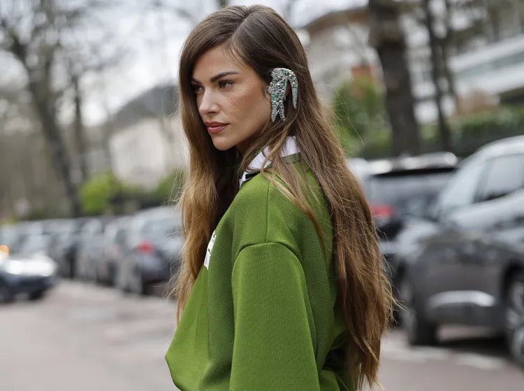 Frau in grüner Kleidung vor einem unscharfen Hintergrund aus Autos und Bäumen