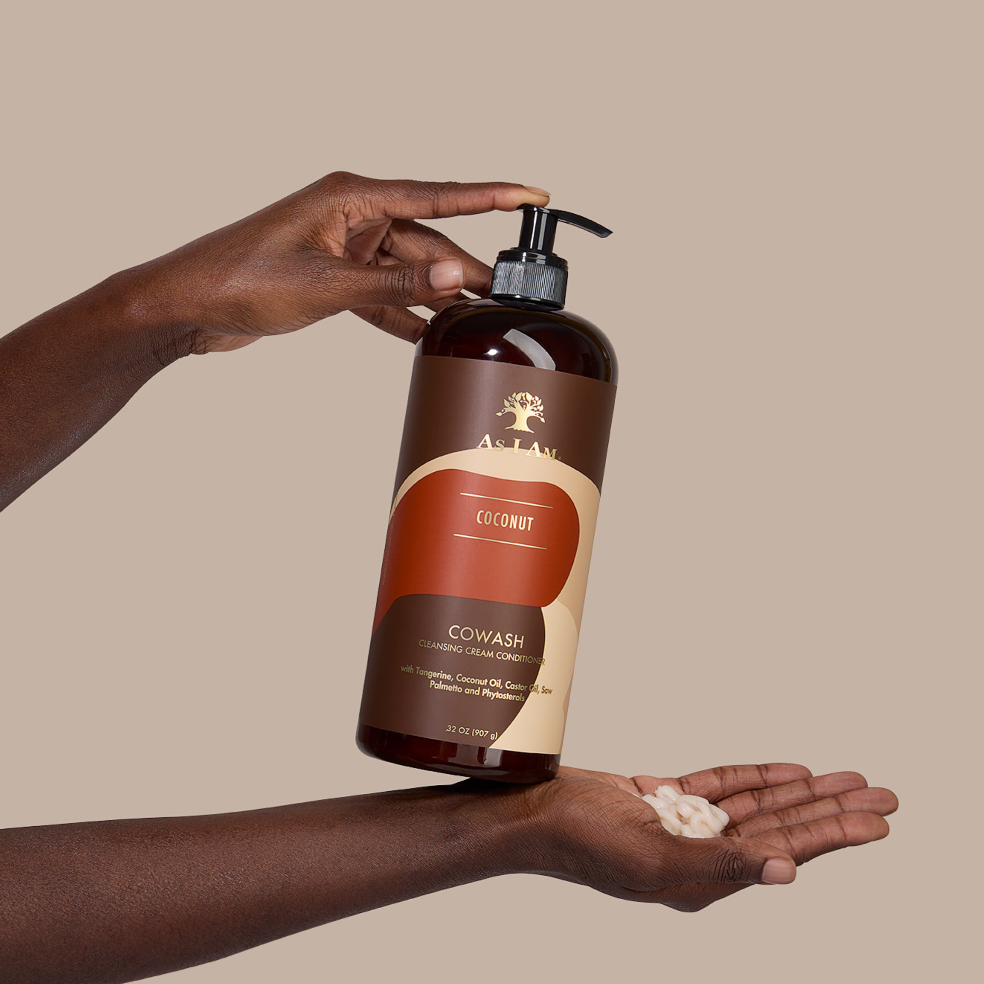 Hand, die eine Flasche As I Am Cowash Coconut Conditioner hält, mit sichtbarer Creme auf der Handfläche vor beigem Hintergrund