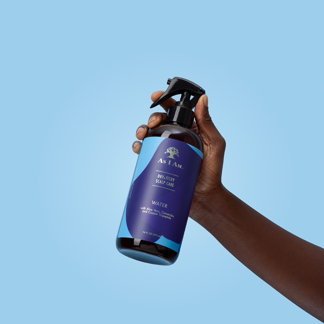 Hand, die eine Flasche AS I AM Deodorant Spray vor einem klaren blauen Hintergrund hält