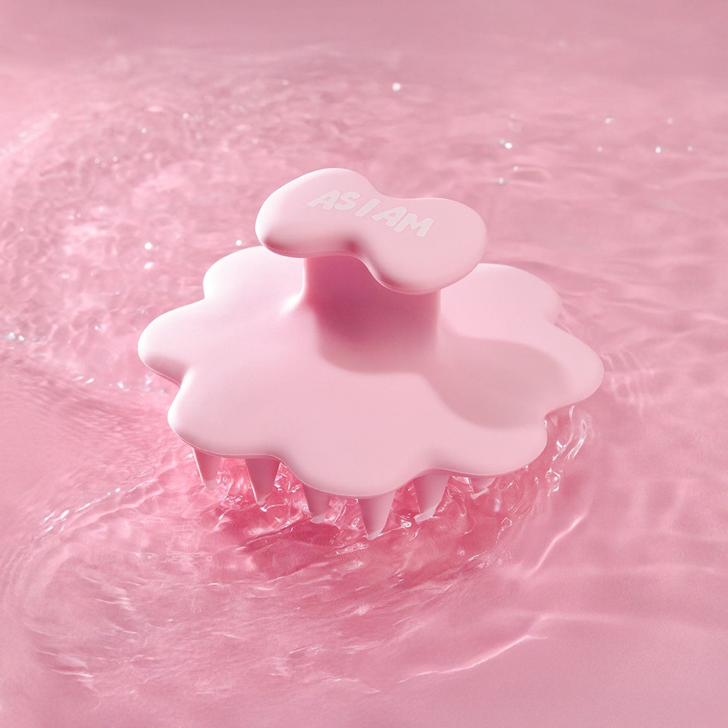 Rosa Kopfhautbürste auf einem rosa Wasserhintergrund