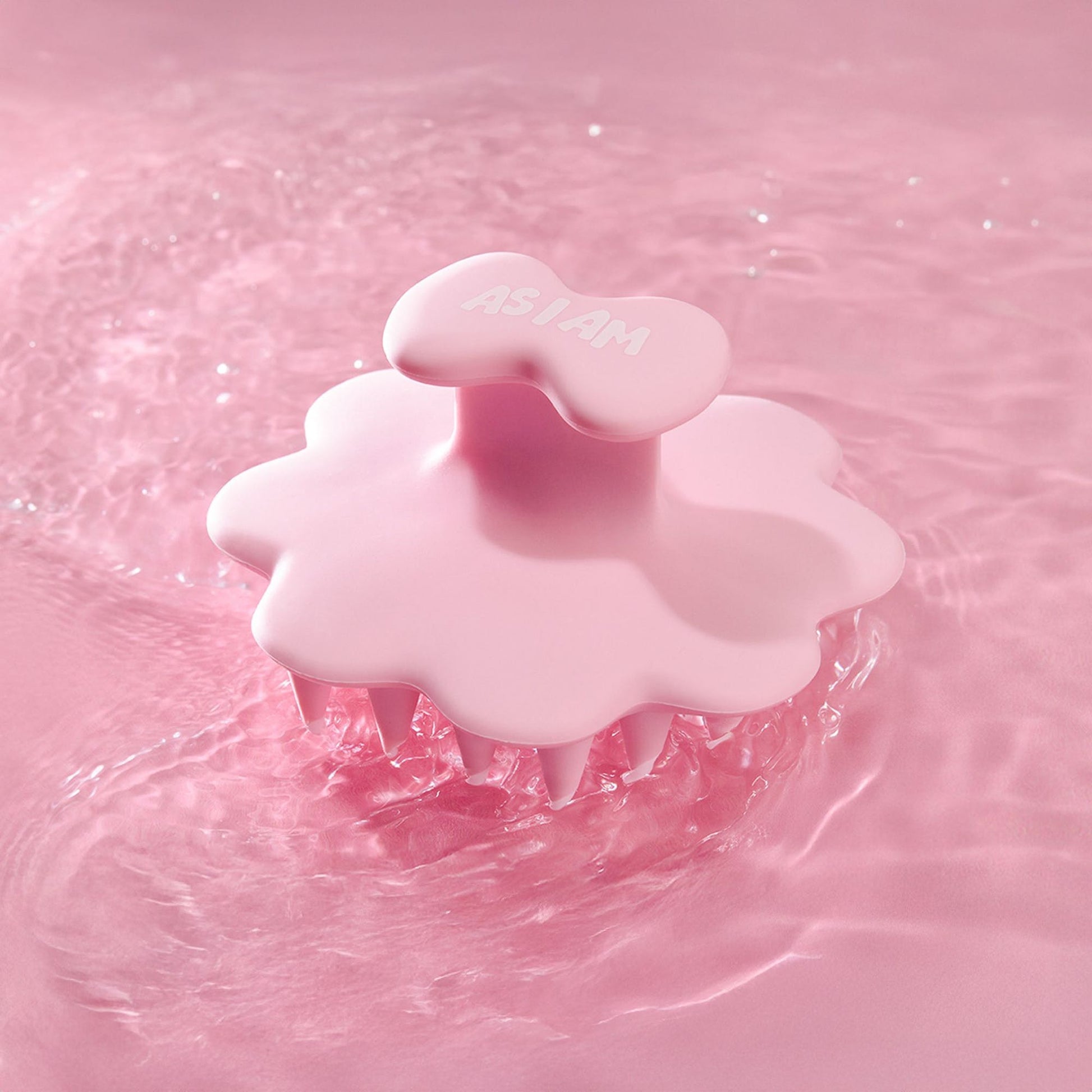 Rosa Kopfhautbürste auf einem rosa Wasserhintergrund