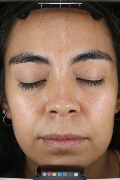 Nahaufnahme des Gesichts einer Person mit geschlossenen Augen, auf dem die Hautstruktur und das Make-up zu sehen sind.