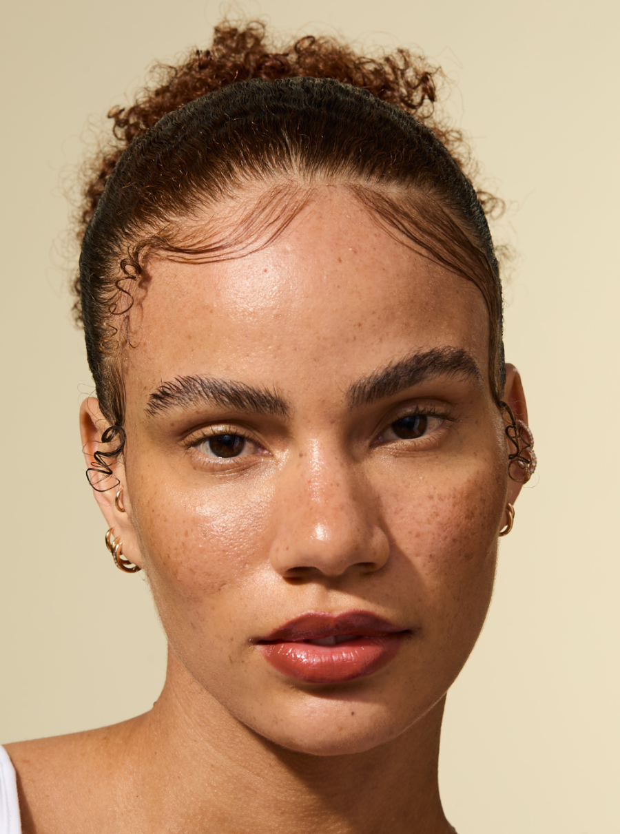 Ein Model mit glatten, geglätteten Kanten und einer ausgefeilten Frisur, die mit dem AS I AM Rosemary Wax Stick gestylt wurde - das Haar erscheint glatt, kräuselfrei und fest an seinem Platz mit einem natürlich wirkenden Finish.