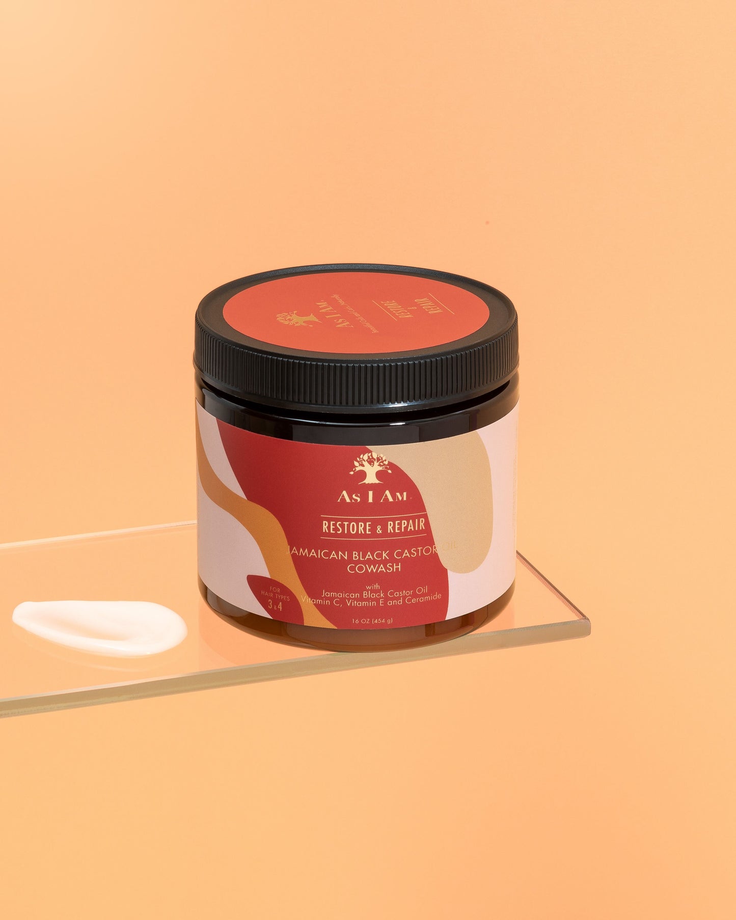 Ein Behälter mit jamaikanischem Black Castor Oil Cowash mit einem Etikett, auf dem die Produktdetails angegeben sind, auf einer reflektierenden Oberfläche mit einem einfarbigen orangefarbenen Hintergrund.